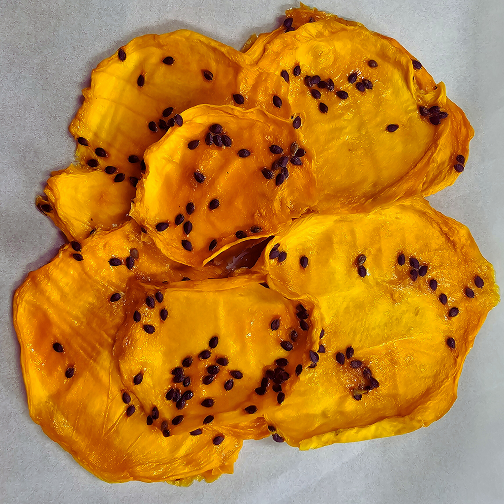 Close-up of dried Australian mango slices infused with passionfruit pulp, showcasing natural texture and passionfruit seeds