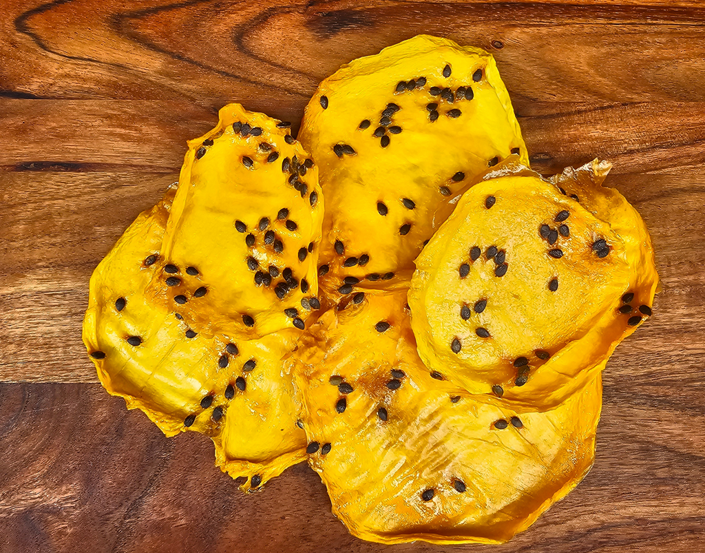 Close-up of Dried Australian Mango with Passionfruit Pulp on a wooden background, showing seeds and vibrant colour.