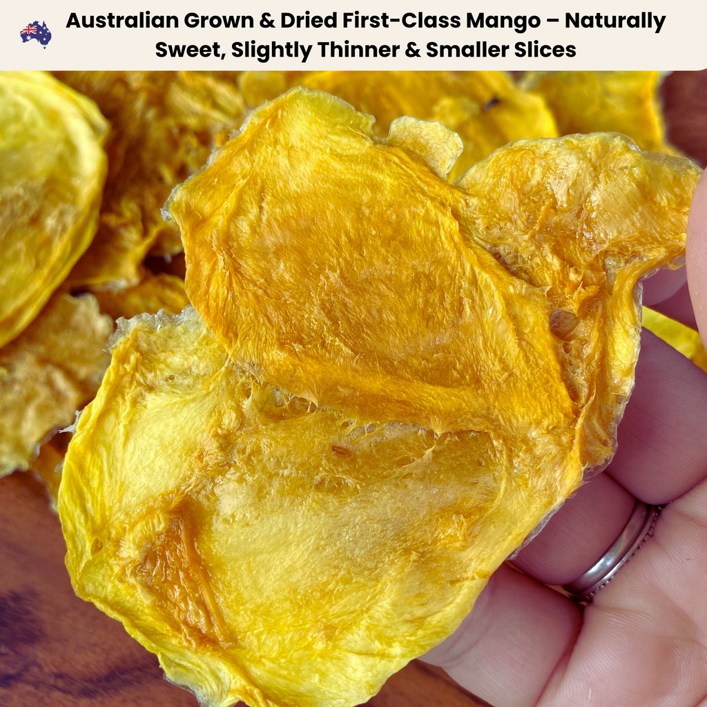 A close-up of a hand holding a piece of First-Class Australian dried mango. The mango slice is naturally golden, slightly thinner, and smaller than premium cuts, maintaining a sweet and chewy texture. Ideal for snacking, smoothies, and bulk buying.